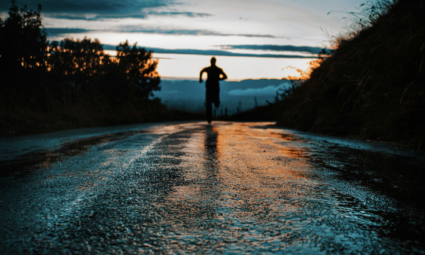 a person running on a wet street at dusk